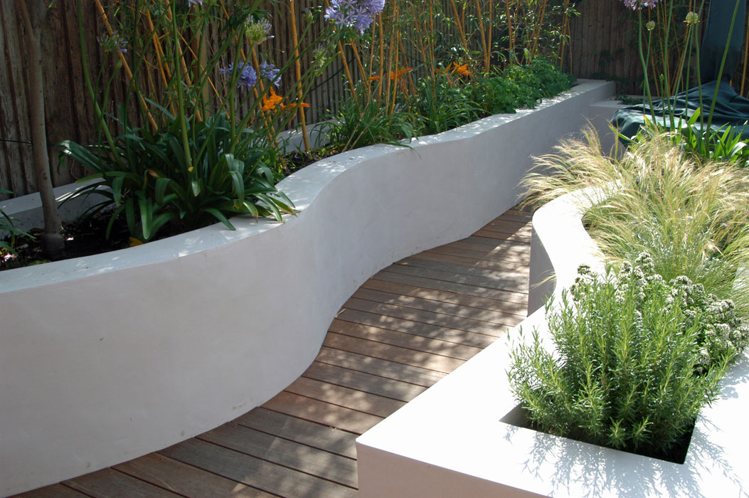 Curvy raised beds either side of deck path with bamboo, herbs and grasses